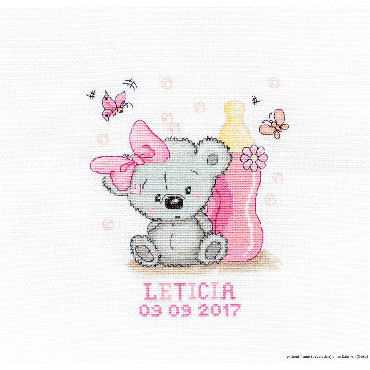 A cross stitch artwork shows a gray teddy bear with a...