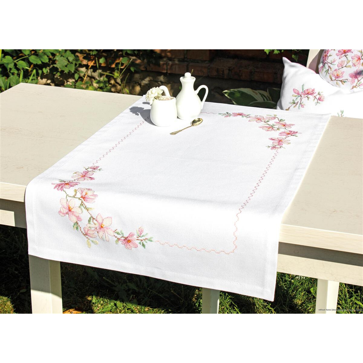 Una mesa blanca, decorada con un camino de mesa bordado...