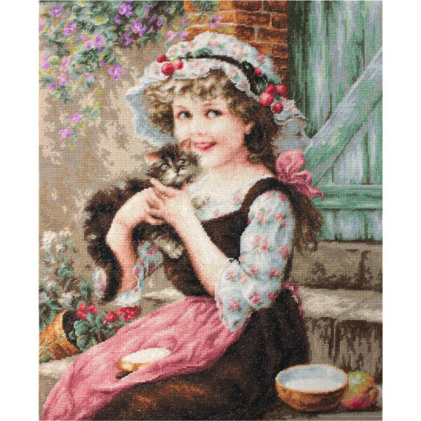 A young girl with curly hair is sitting outside. She is wearing a hood decorated with cherries, a dress with flowered sleeves and a pink apron. She smiles and holds a small, fluffy kitten in her arms. Behind her is a rustic brick wall and a wooden door with blooming flowers. On her lap lies her Luca-s embroidery pack next to sliced bread in a bowl.