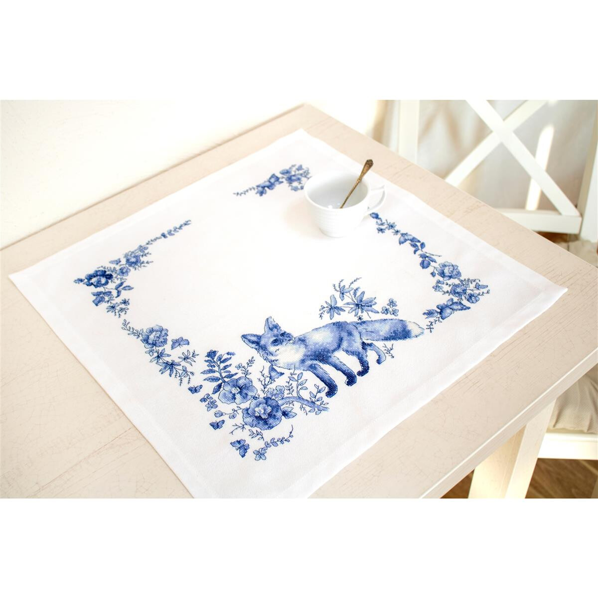 A white square placemat with a blue floral border and a...