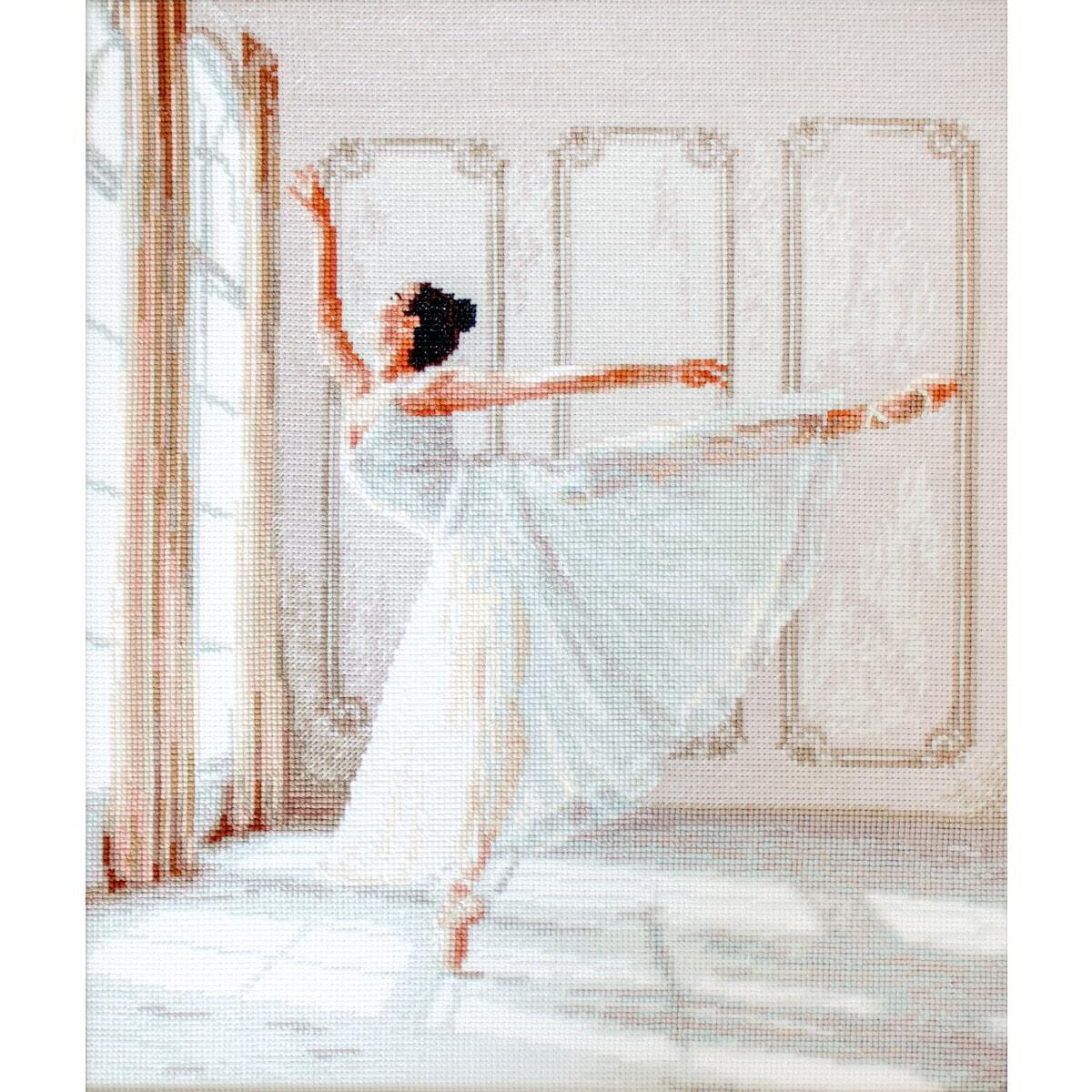 A ballet dancer in a white dress performs an arabesque in...
