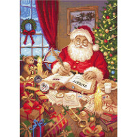 Дед Мороз сидит за столом в своем классическом красно-белом костюме и пишет ручкой в книге с надписями Добро и Зло. Его окружают завернутые подарки, свечи, плюшевый медведь и вышитая пачка Letistitch. На заднем плане видна елка с украшениями и окно со снегом за окном.