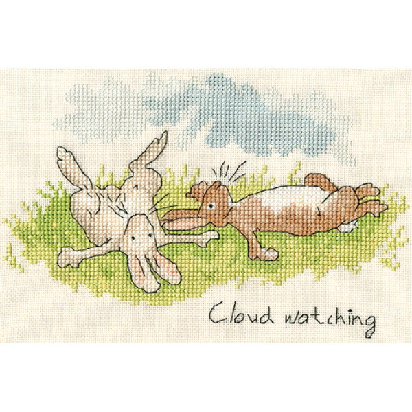 Stickpackung mit zwei Kaninchen, die auf grünem Gras liegen und in einen blauen Himmel mit hellgrauen Wolken blicken. Ein Kaninchen ist beige und liegt auf dem Rücken mit den Pfoten in der Luft, und das andere Kaninchen ist braun und liegt auf der Seite. Unten rechts sind die Worte „Cloud watching“ aufgestickt. Marke: Bothy Threads