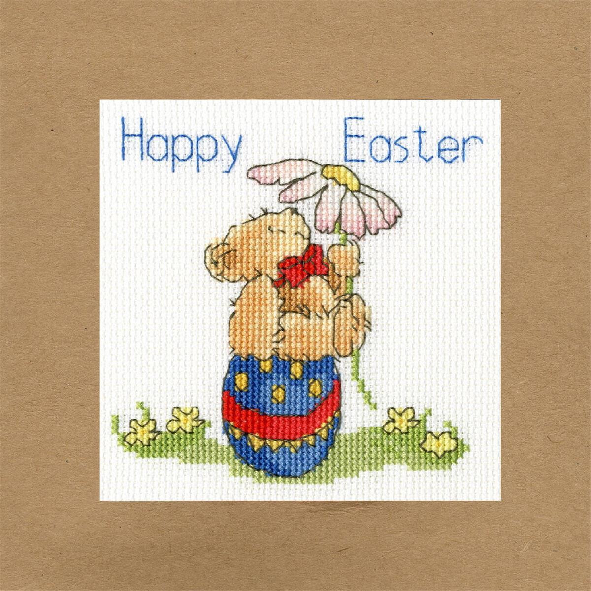 A cross-stitch illustration on beige paper shows a teddy...