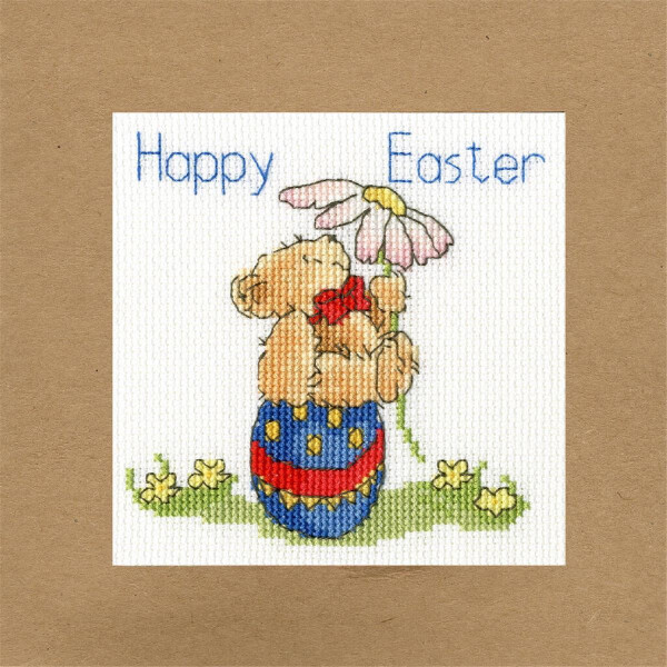 A cross-stitch illustration on beige paper shows a teddy bear holding a large daisy and sitting in an Easter egg decorated with stripes and dots. The text at the top reads Happy Easter. Small yellow flowers surround the teddy bears feet, creating a charming embroidery pack in the classic Bothy Threads style.