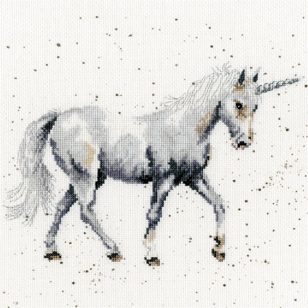 An embroidery pack from Bothy Threads featuring a unicorn in mid-crotch with its head slightly lowered and its horn clearly visible. The embroidery features shades of white, gray and subtle brown, with patches around the unicorn giving the background a textured, almost glittery look.