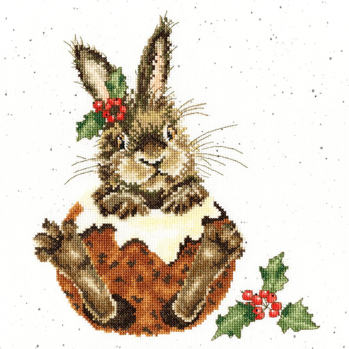 Cross stitch picture of a cheerful brown bunny sitting in...