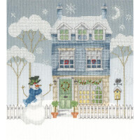 Un paisaje invernal bordado en punto de cruz (paquete de bordado, Bothy Threads) muestra una casa azul claro de tres plantas decorada con una corona navideña y rodeada de árboles desnudos y copos de nieve. Delante de la casa hay una valla blanca, un muñeco de nieve con sombrero, bufanda y nariz de zanahoria. A la derecha hay una pajarera.