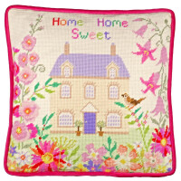 A square cushion with red piping around the edges and a pastel needlepoint pattern. The embroidery pack from Bothy Threads shows a two-storey house surrounded by various bright flowers. Above the house, the words Home Sweet Home are embroidered in colorful letters using cross stitch technique.