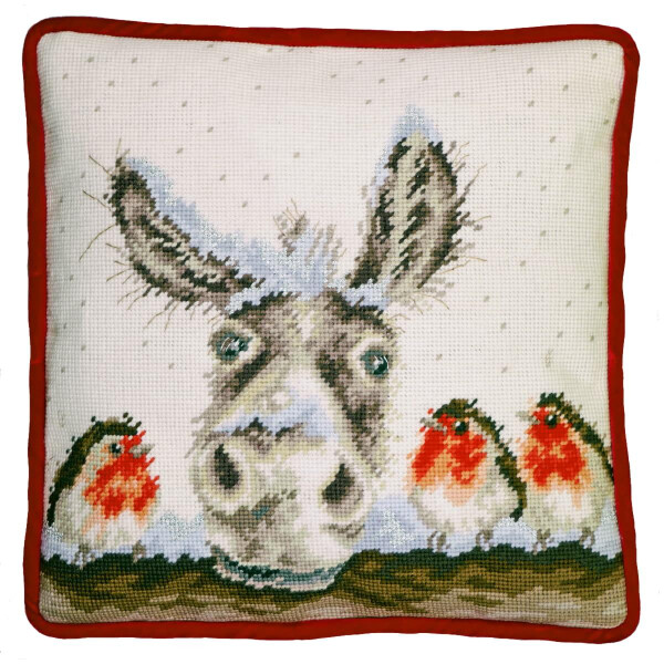 A square cushion with a red border shows a cross-stitch pattern in the center with a donkey with large eyes. Three small birds with red breasts and brown wings sit on a branch to the right of the donkey. The background is white with small, scattered light blue dots. This is the embroidery kit from Bothy Threads.