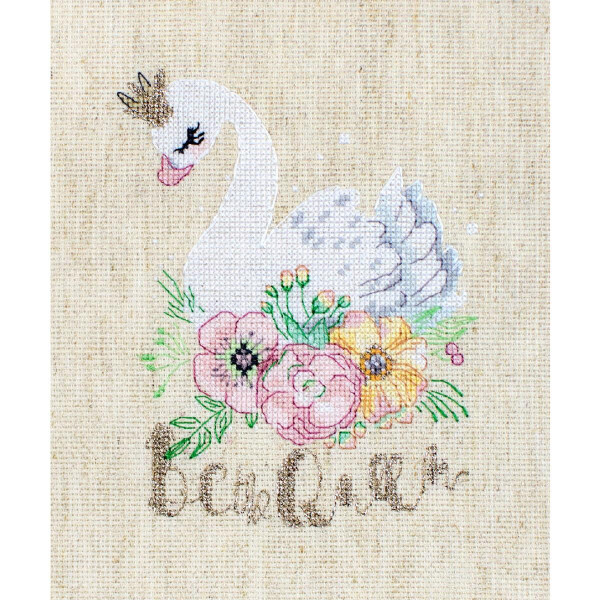 A cross-stitch pattern on light beige fabric shows a white swan with a golden crown and pink beak. The swan is surrounded by colorful flowers, including pink, yellow and orange blossoms with green leaves. The word believe is embroidered in gold thread under the swan and flowers. Perfect for fans of embroidery packs from Letistitch!
