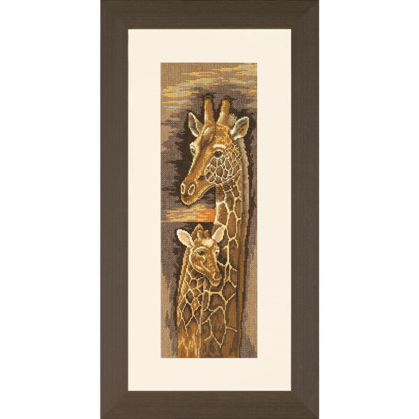 Ein gerahmtes Kreuzstich-Kunstwerk (Stickpackung von Lanarte) zeigt zwei Giraffen; eine erwachsene Giraffe mit langem Hals und deutlichen Flecken steht neben einer kleineren Giraffe. Der Hintergrund weist einen Farbverlauf in Erdtönen auf, der an einen Sonnenuntergang oder Sonnenaufgang erinnert. Der Rahmen ist schlicht und dunkel, mit einer weißen Matte um das Kunstwerk.