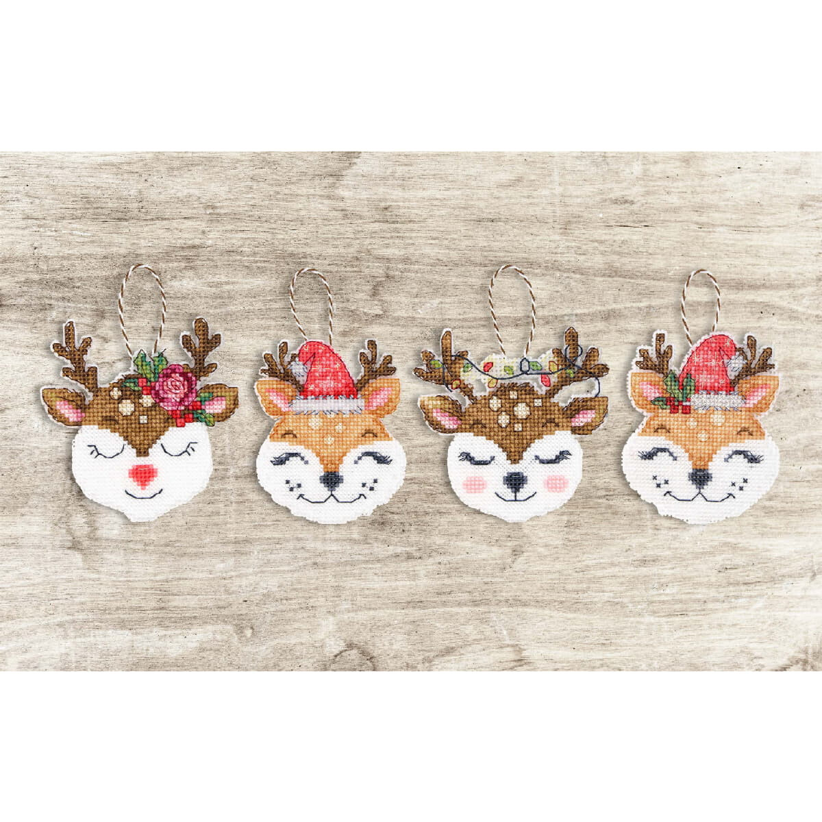 Four festive reindeer ornaments in cross stitch on a...