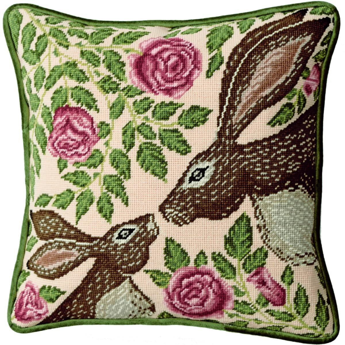 An embroidered picture of two brown rabbits with pink...