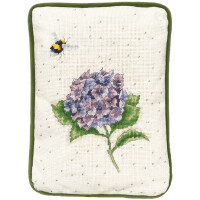 На прямоугольном вышитом пакете от Bothy Threads изображен фиолетовый цветок гортензии с зелеными листьями на белом фоне с мелкими бежевыми точками. Над цветком вышита желто-черная пчела. Края изделия окантованы зеленой тканью.