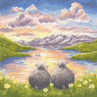 Eine farbenfrohe, gestickte Landschaft (Stickpackung) von Bothy Threads zeigt zwei Schafe, die auf einem grasbewachsenen Hügel mit weißen Blumen sitzen und bei Sonnenuntergang auf einen ruhigen See blicken. Der Himmel ist mit rosa und orangefarbenen Wolken übersät, in der Ferne spiegeln sich Berge im Wasser. Ein kleines Segelboot schwimmt auf dem See und vervollständigt die friedliche Szene.