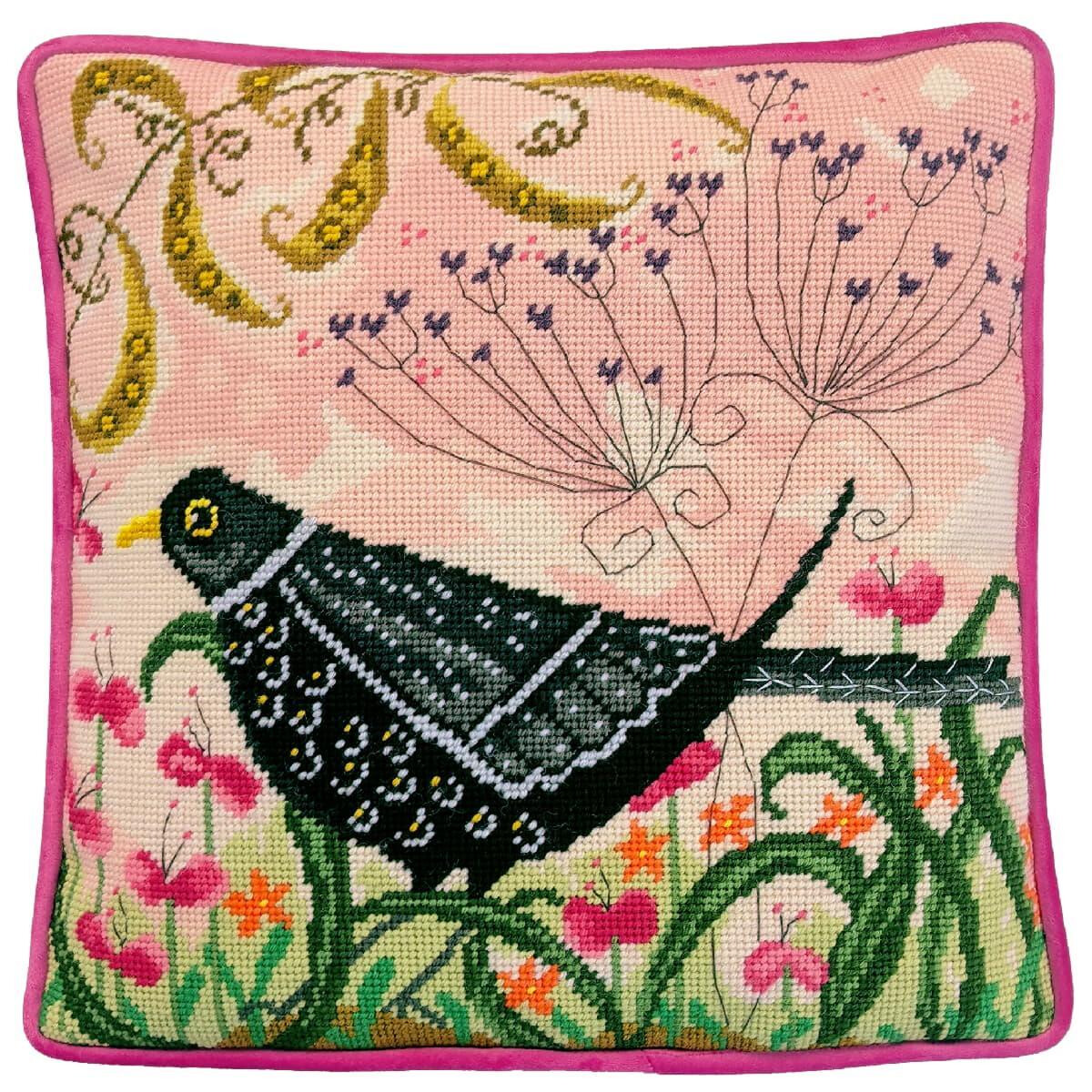 A square cushion with a colorful embroidery of a black...