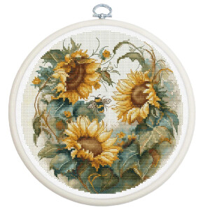 A circular embroidery design features a bright trio of sunflowers with rich, golden petals and lush green leaves. A bee hovers near the sunflower in the center. This Luca-s embroidery pack is framed by a white embroidery hoop and the detailed stitching captures the natural beauty of the flowers and bee.