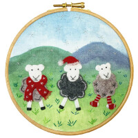 В рамке для вышивки изображены три овечки на фоне травянистого пейзажа с зелеными холмами и голубым небом. Одна из овец одета в красный шарф, другая - в шапку Санта-Клауса и черный джемпер, а третья - в серый джемпер и полосатые носки. Детальная вышивка в этом наборе от Bothy Threads придает текстуру причудливой сцене.