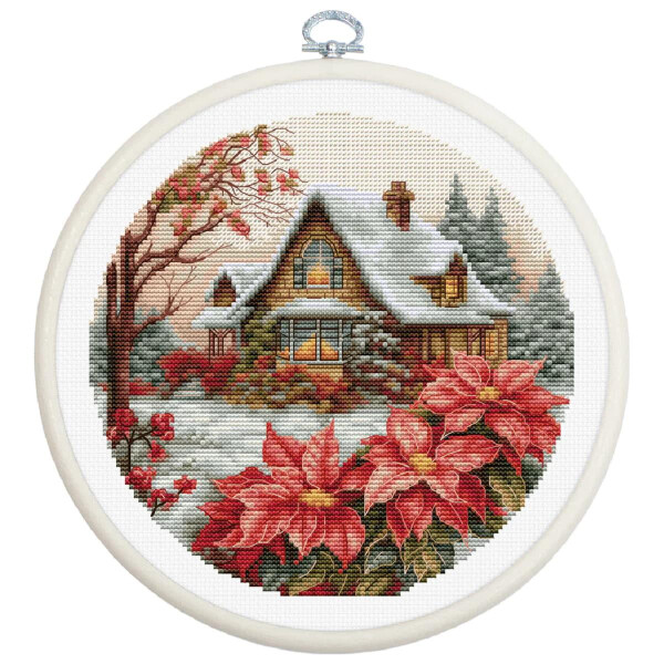 A cross-stitch embroidery from a Luca-s embroidery pack shows a cozy cottage in a snowy landscape, depicted in a round embroidery hoop. The cottage is surrounded by tall trees and in the foreground are large, bright red poinsettias that evoke a wintry vacation atmosphere.
