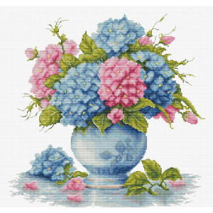 A cross stitch design showing a bouquet of blue and pink hydrangeas with green leaves in a white vase with blue flower patterns. Several flowers and leaves lie on the reflective surface beneath the vase. This intricate embroidery pack from Luca-s features detailed stitching for a realistic look.