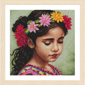 A Lanarte embroidery pack artwork shows a young girl with closed eyes wearing a floral wreath of red, pink and yellow flowers. She has long, dark hair and is wearing a colorful outfit with vibrant patterns. The background is a soft, muted green. The work is framed in a light-colored wooden frame.