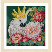 A framed Lanarte embroidery pack depicting a white cockatoo with a yellow crest. The bird is surrounded by large pink, red and white flowers with green leaves, all against a dark green background. The frame is a light wood color.